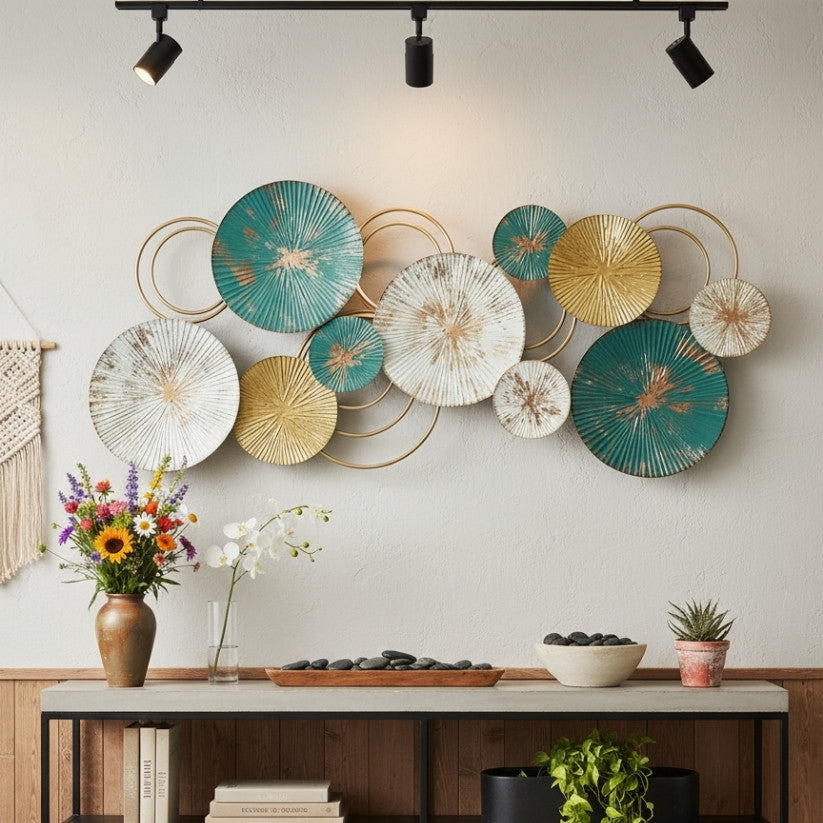 Decorative wall art with circular metal plates in teal, gold, and white above a table with decorative items.