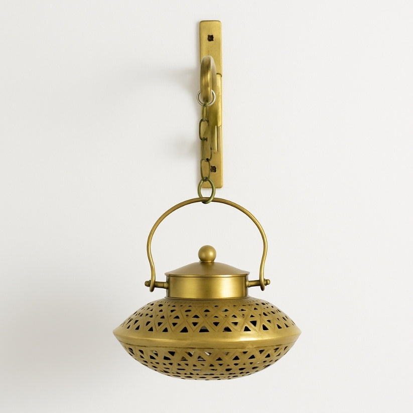 Brass hanging lantern with decorative design on a light gray background