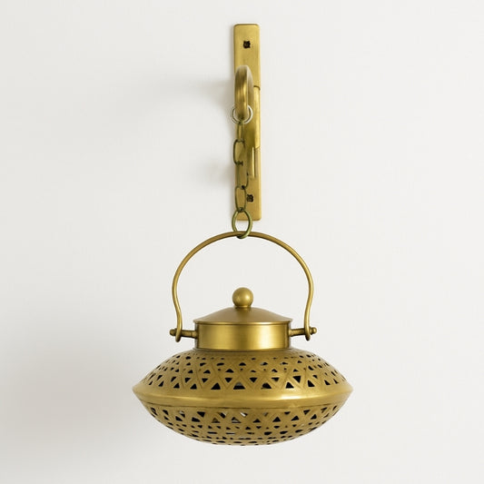 Brass hanging lantern with decorative design on a light gray background