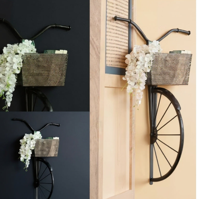 Decorative bicycle with basket and floral arrangement on a wall.