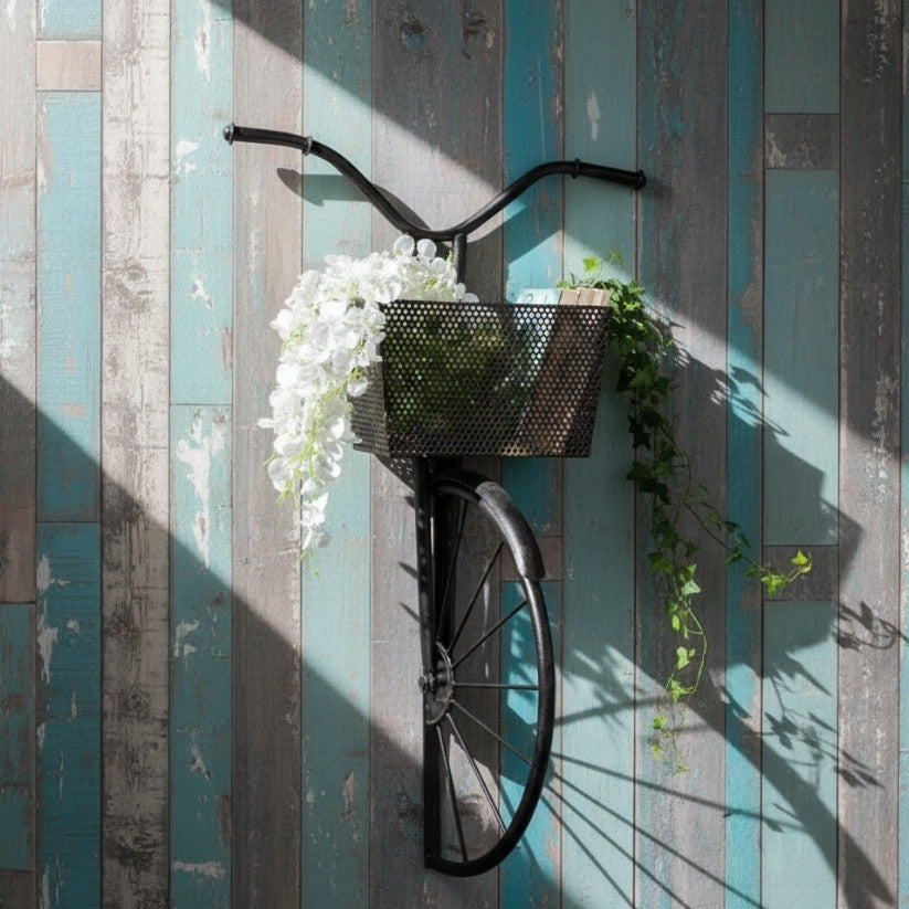 Decorative bicycle with a basket of flowers against a wooden wall.