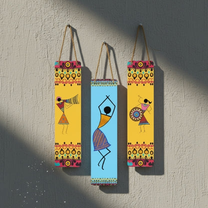Three colorful wall hangings with abstract designs of people on a textured wall.