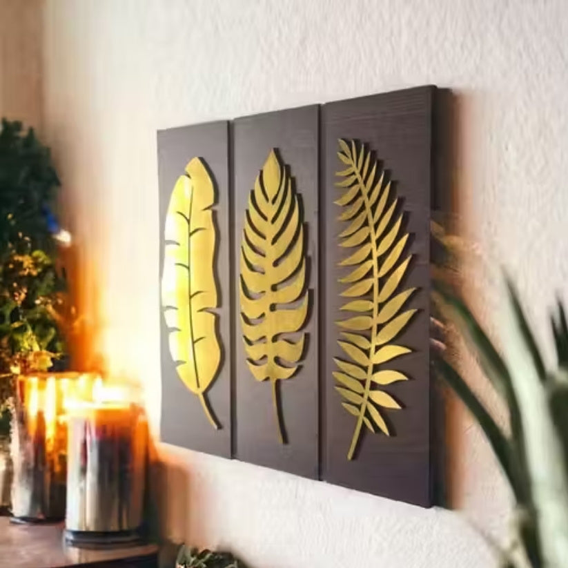 Decorative wall art with gold leaf designs on a wooden panel, placed in a warm indoor setting.