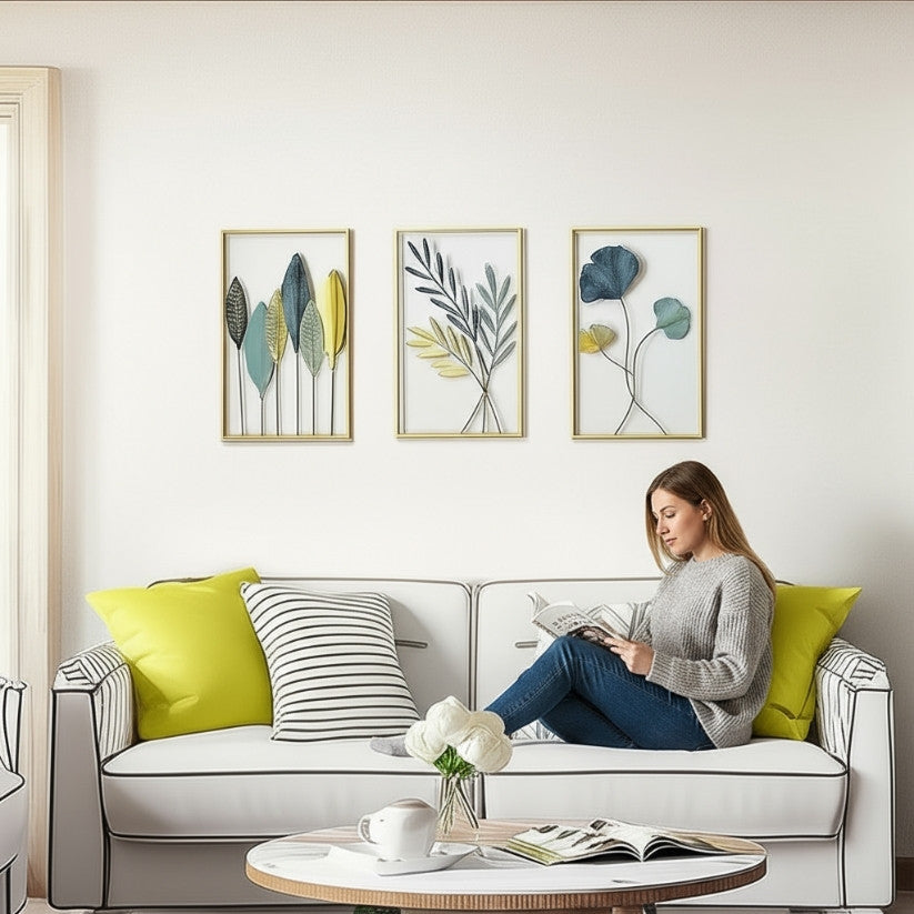 Woman reading a book on a white sofa with decorative pillows and wall art in a living room.